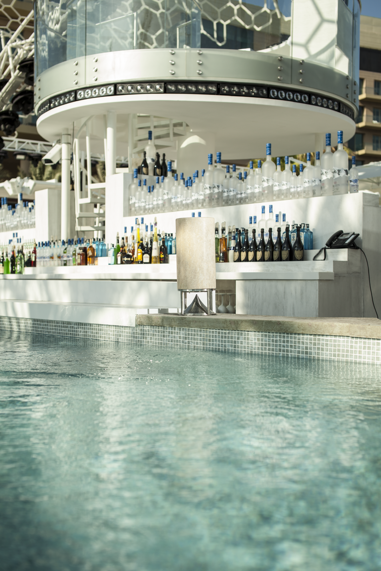 Bodenlautsprecher Blick auf einen modernen Poolbereich mit einer barähnlichen Struktur im Hintergrund.