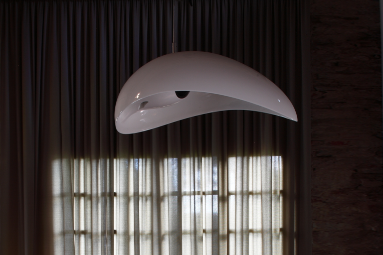 Designlautsprecher Moderne, geschwungene Deckenlampe in einem Raum mit Vorhängen.