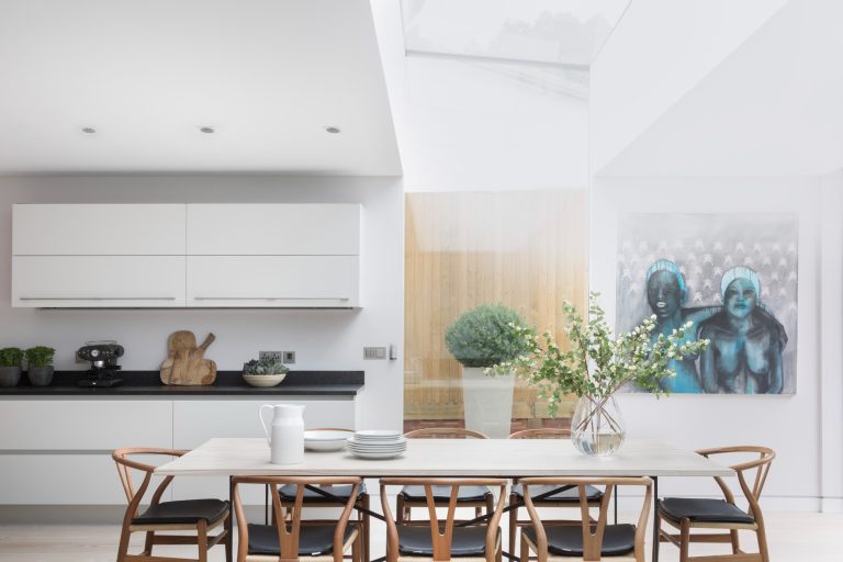 Deckenlautsprecher Moderne, helle Küche mit Esstisch, Pflanzen und einer auffälligen Wandkunst.