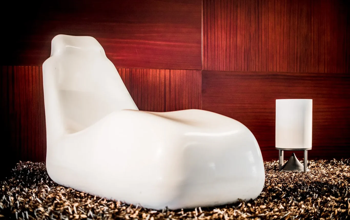 Bodenlautsprecher Weiße Relaxliege auf einem Kiesbett vor einer Holzverkleidung.