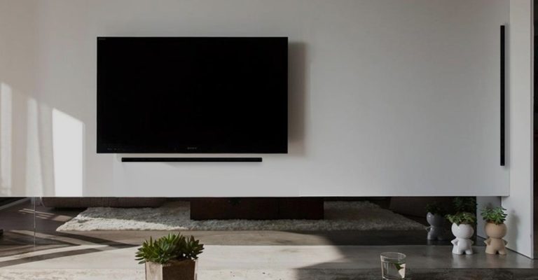 Modernes Wohnzimmer mit einem großen, flachen Fernseher an der Wand und einem Teppich.