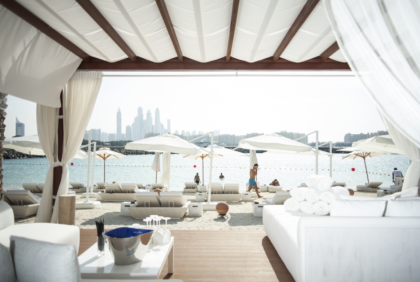 Bodenlautsprecher Blick auf eine strandnahe Lounge mit Sonnenliegen und Sonnenschirmen.